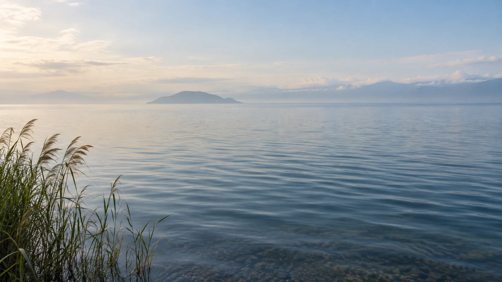 朝の琵琶湖の穏やかな水面と遠くに浮かぶ島影