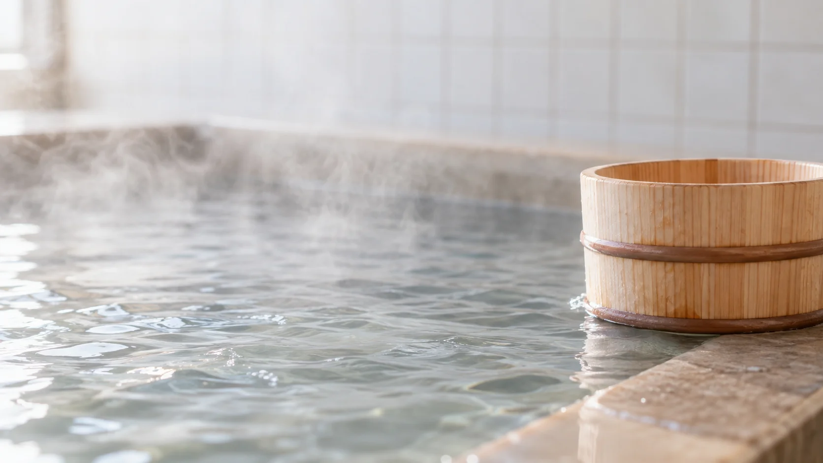 湯気の立つお湯のふちに置いた木の手おけ
