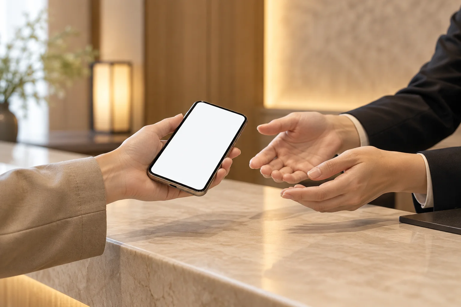 ホテルのフロントカウンターでスマートフォンの画面を見せる手元のイメージ