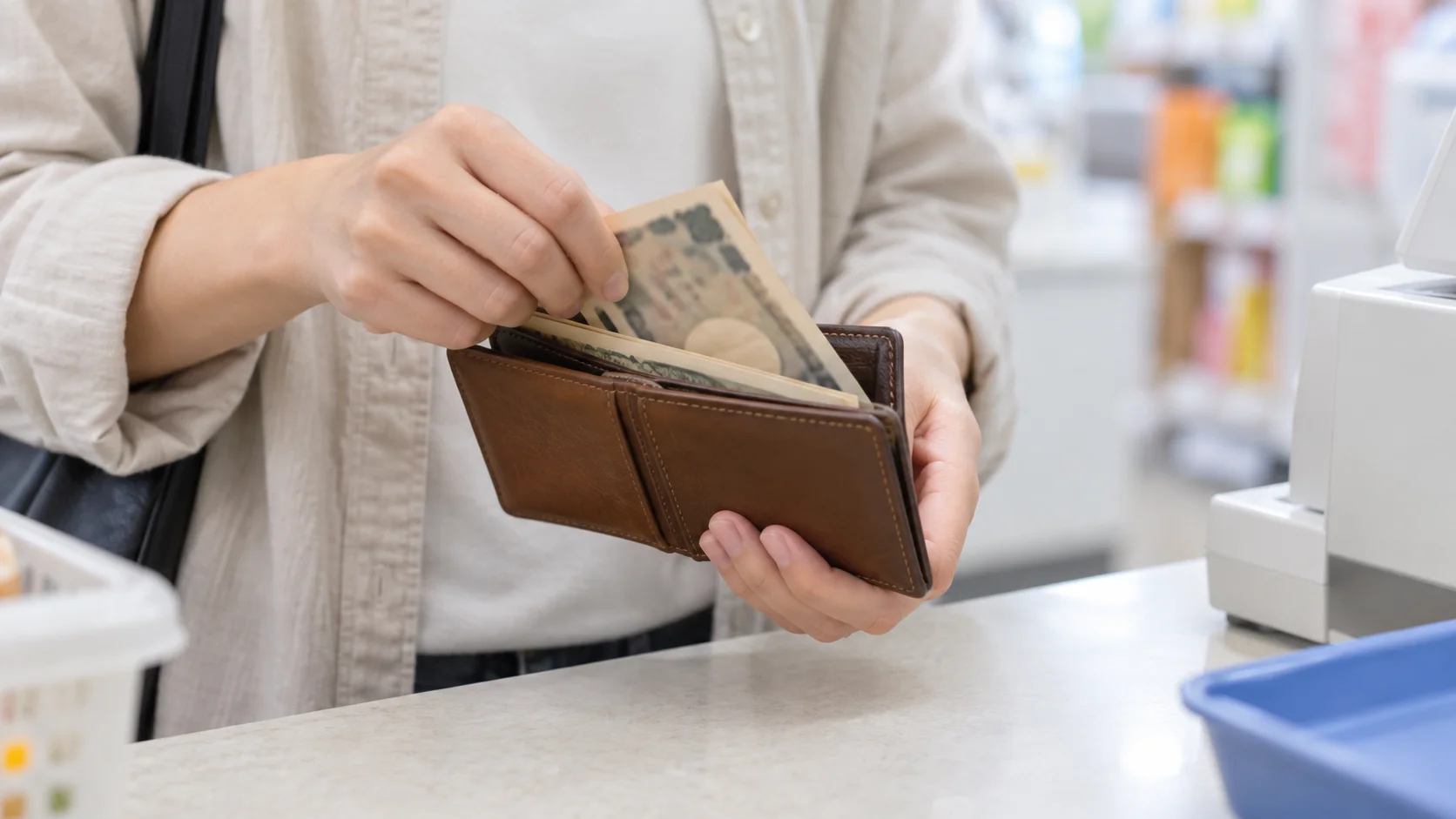 コンビニの支払い端末と財布を持つ手元のイメージ