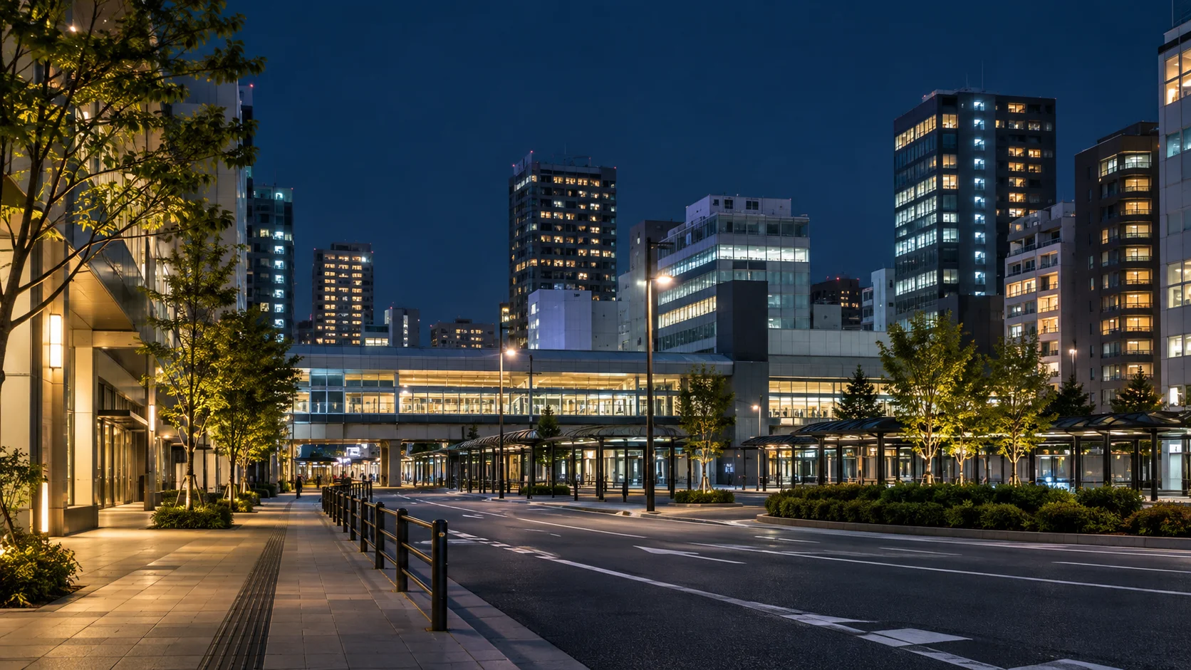 夜の駅前に並ぶビルと明かりのついた窓