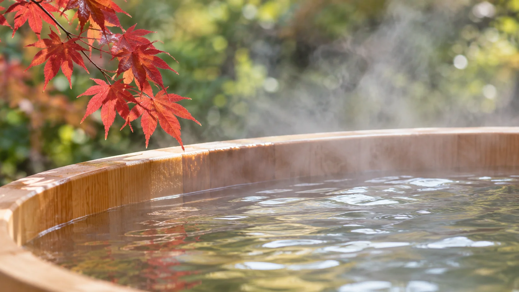 紅葉の下で湯けむりが立つ檜の露天風呂