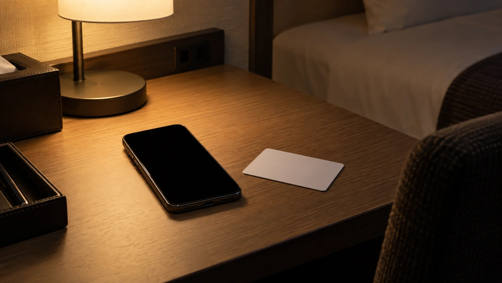 夜の客室の机に置かれたスマートフォンとカードキー